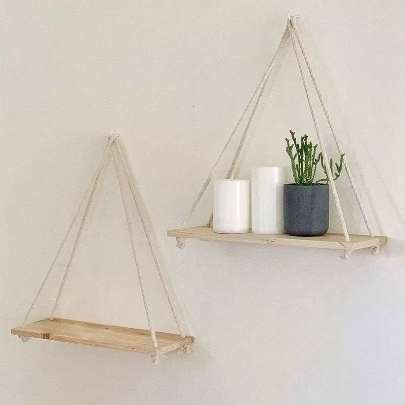 Boho wood rope hanging wall shelves set featuring two minimalist floating shelves with rope suspension displaying candles and a potted plant on a neutral wall