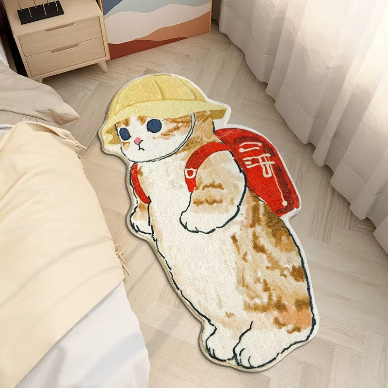 Cute cat shaped rug wearing hat and red backpack placed on bedroom floor beside bed, soft cartoon animal mat for kids room decor