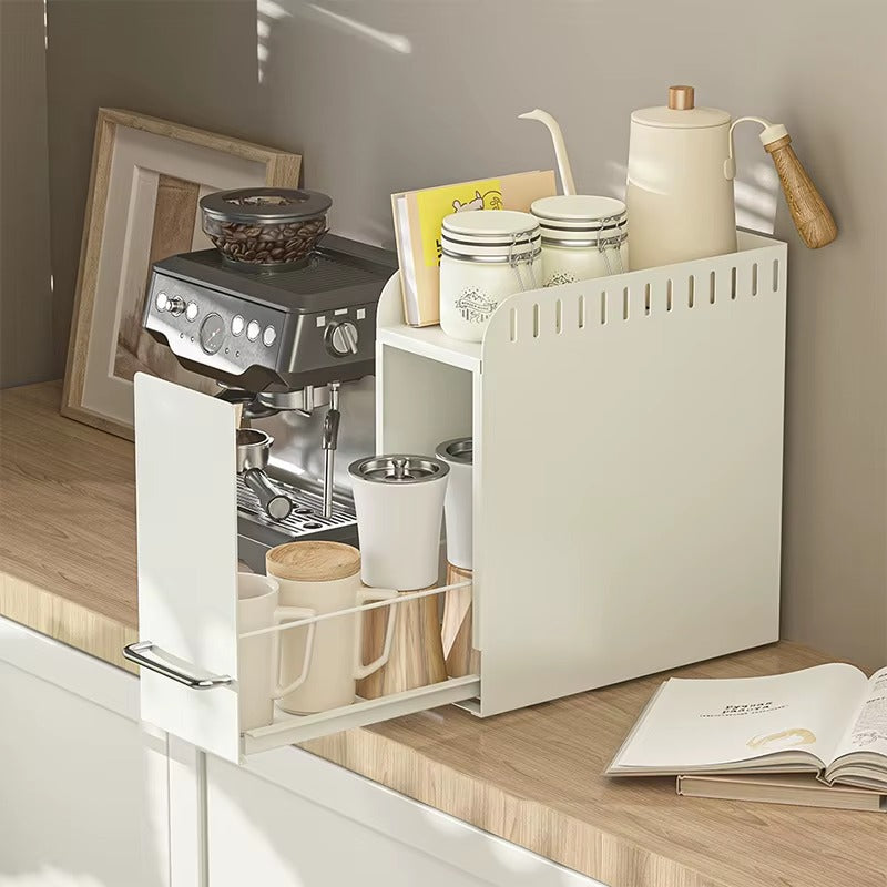 Pull-out countertop organizer used as a coffee station holding cups, jars, and accessories next to espresso machine.