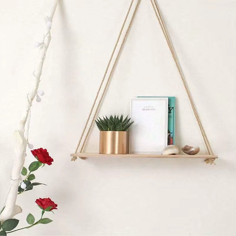 Hanging shelf with a plant, picture frame, and decorative items on a white wall.