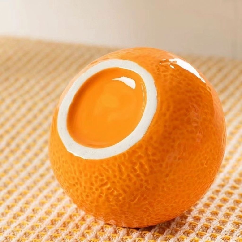 Bottom view of a glossy orange-shaped ceramic vase showing smooth glazed interior and textured outer surface.