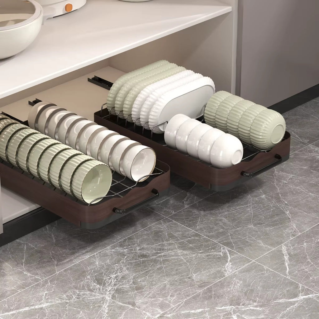 Pull-out cabinet dish drying rack with trays holding plates, bowls, and cups neatly organized inside a kitchen cabinet.