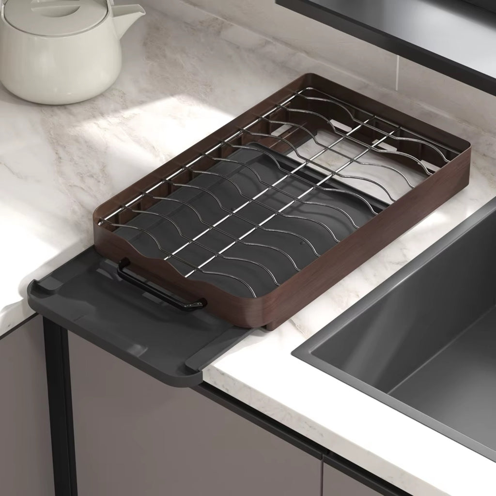 Pull-out cabinet dish rack organizer with metal slots and drip tray, shown empty next to a kitchen sink.