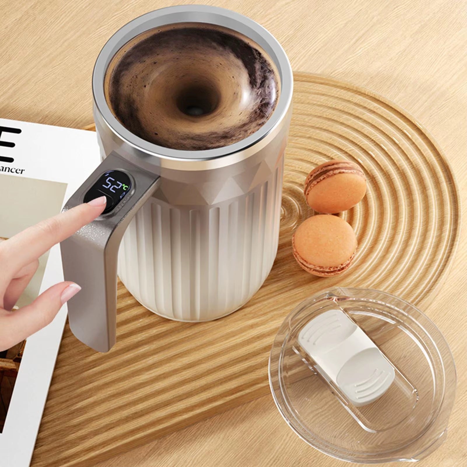 Smart coffee mug with built-in digital temperature display on the handle, showing real-time drink temperature while holding hot coffee on a wooden tabletop.